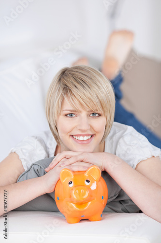 Foto: lachende blonde frau mit sparschwein lachende blonde frau mit sparschwein