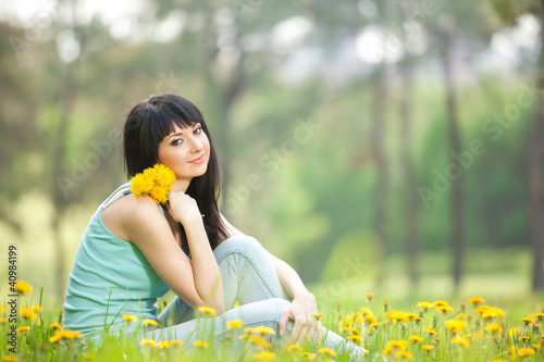 Photo: Cute woman in the park with dandelions Cute woman in the park with dandelions