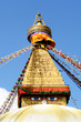 stupa with buddha eyes and prayer flags on blue sky background