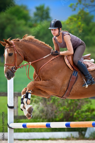 Foto: Young girl jumping with chestnut horse Young girl jumping with chestnut horse