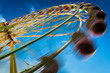 Blurry ferris wheel in motion on blue sky background
