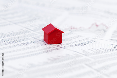 Photo: Page of stock market prices with red model house Page of stock market prices with red model house