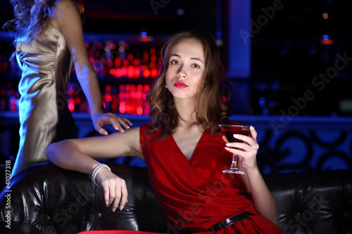 Photo: Young woman in night club with a drink Young woman in night club with a drink