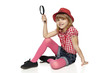 Full length of little girl sitting on the floor with magnifier