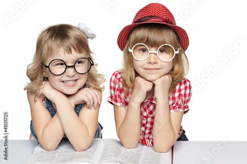 Photo: Two little girls in funny eyeglasses reading book Two little girls in funny eyeglasses reading book