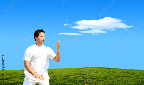 Photo: Young man practicing Tai Chi on grassy hill Young man practicing Tai Chi on grassy hill