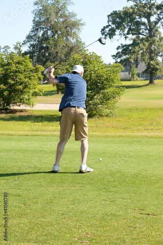 Photo: Male golfer teeing off with driver Male golfer teeing off with driver