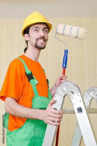 Photo: Painter worker during painting job Painter worker during painting job