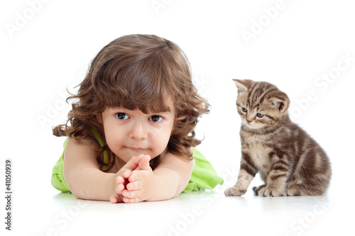 Photo: Funny child lying on floor. Scottish kitten sitting near girl. Funny child lying on floor. Scottish kitten sitting near girl.