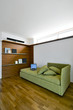 divano verde con boiserie e parquet in mansarda