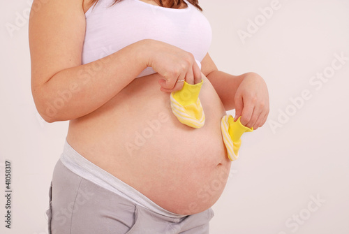 Photo: Pregnant woman holding yellow booties Pregnant woman holding yellow booties
