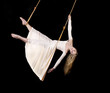 Foto: Young woman gymnast in white dress on rope on black background Young woman gymnast in white dress on rope on black background