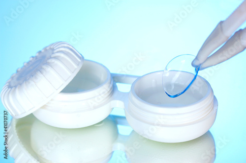 Photo: contact lenses in containers and tweezers on blue background contact lenses in containers and tweezers on blue background