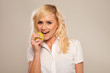 Blonde woman is preparing to bite a green apple