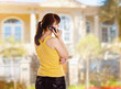 A young woman with a cellphone outdoors, back-view