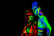 Man and woman with fluorescent bodyart. Black background. Studio