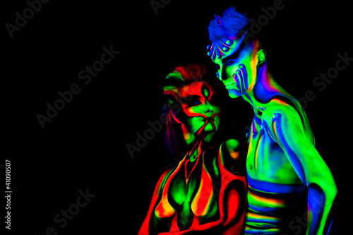 Photo: Man and woman with fluorescent bodyart. Black background. Studio Man and woman with fluorescent bodyart. Black background. Studio
