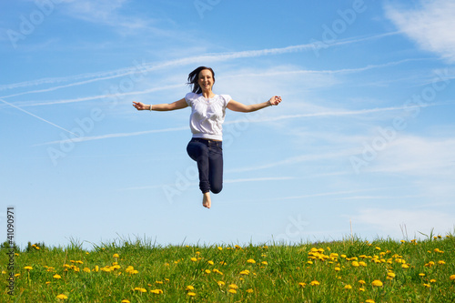 Foto: smiling young girl jumping against blue sky smiling young girl jumping against blue sky