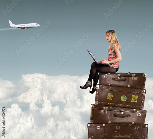 Photo: Beautiful blond girl sitting on suitcases above clouds Beautiful blond girl sitting on suitcases above clouds