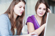 Two female college students working on a laptop computer during