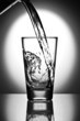 water pouring into a glass on a reflective surface