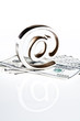 At symbol paperweight on a pile of 100 dollar bills