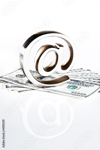 Photo: At symbol paperweight on a pile of 100 dollar bills At symbol paperweight on a pile of 100 dollar bills