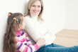 Pretty young mom sitting on the floor at home with her daughter