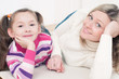 Smiling little girl and her mom lying on the floor at home