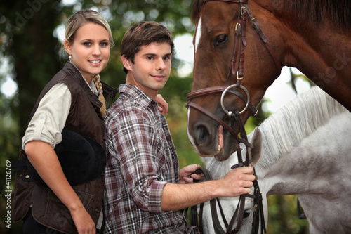 Foto: Young couple stood by horses Young couple stood by horses