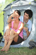 Man offering flowers to a woman in front of a tent