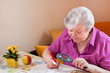 Seniorin rätselt mit Hilfe einer Lupe