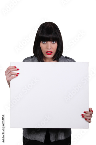 Photo: a woman looking amazed and showing a white panel a woman looking amazed and showing a white panel