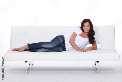 Photo: Female model laid on expensive leather sofa Female model laid on expensive leather sofa