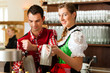 Junger Mann in Tracht zapft ein Bier im Restaurant