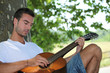 Man playing guitar under tree Man playing guitar under tree