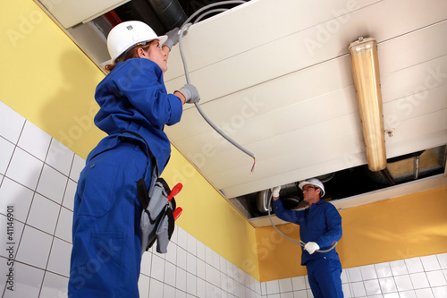 Photo: Two electrician working on ceiling wiring Two electrician working on ceiling wiring