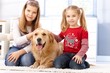 Little sisters fondling dog at home