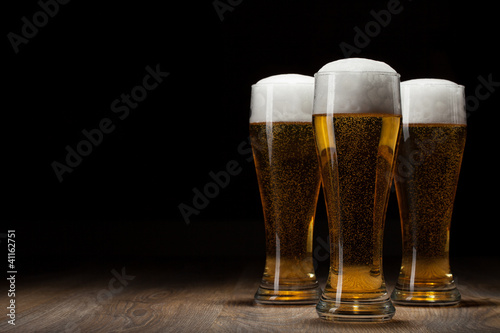 Photo: three glass beer on wooden table with copyspace three glass beer on wooden table with copyspace