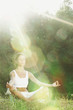 Young woman doing yoga exercise in green park