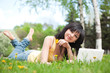 Cute woman with white laptop in the park with dandelions