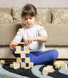 The little girl plays wooden toy cubes