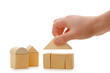 The hand establishes a toy roof on wooden cubes