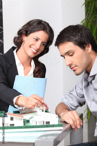 Foto: businesswoman showing a model of a house to a client businesswoman showing a model of a house to a client