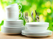 Clean dishes on wooden table on green background