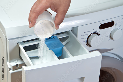 Photo: Man pours detergent into the washing machine Man pours detergent into the washing machine