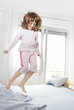 happy little girl jumping on a bed after waking happy little girl jumping on a bed after waking
