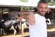 Farmer with pitchfork standing in front of cattle