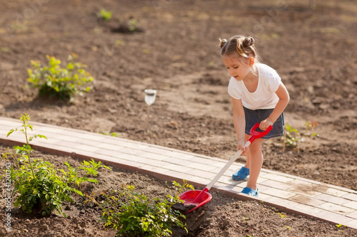 Foto: Cute Little girl gardening in summer day Cute Little girl gardening in summer day
