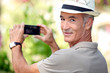 Middle -aged man taking photo whilst wearing straw hat